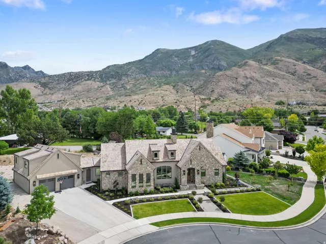 Stone and shake-sided residence featuring a multi-car garage, manicured front lawn, and paved driveway