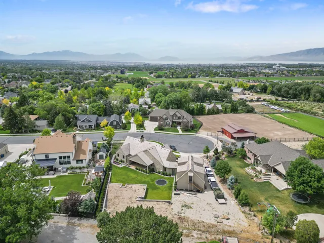 Suburban landscape featuring a cul-de-sac, residential properties with varied architectural styles, and distant mountains