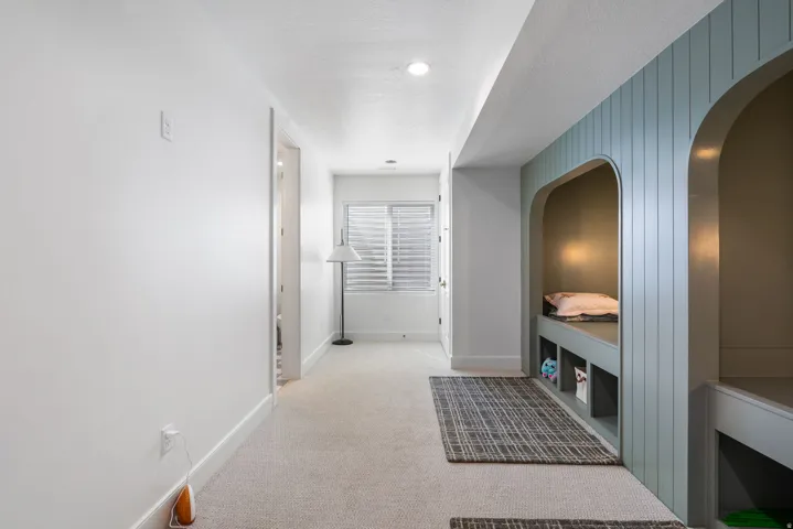 Carpeted area featuring built-in arched nooks with beadboard paneling, integrated bench seating, and storage compartments