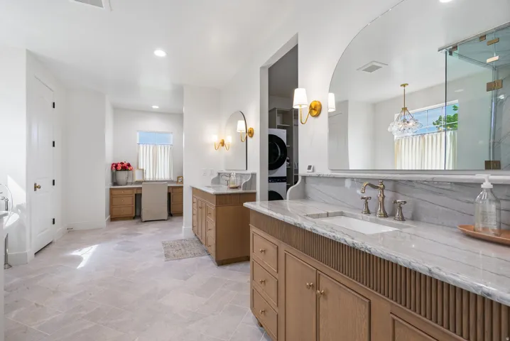 Light-toned tiled flooring complements the dual wood-finish vanity with stone countertops and undermount sinks