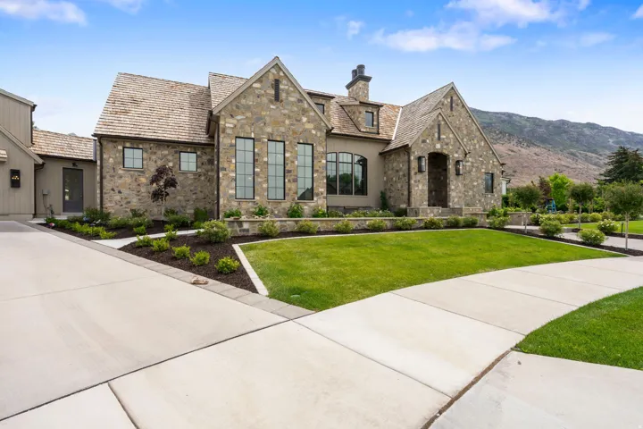 Stone exterior with wood-shingle roofing, featuring a covered entry and a concrete driveway