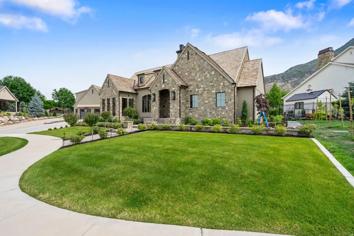 Stone and stucco exterior featuring multiple gables and a cedar shake roof