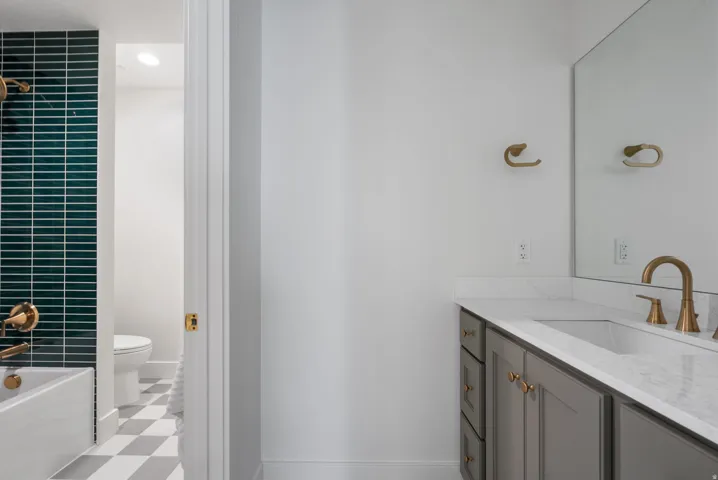Bathroom featuring a vanity with a light gray cabinet, white countertop, and gold-finish fixtures