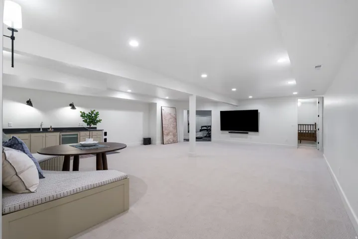 Expansive finished basement featuring a built-in wet bar with cabinetry, sink, and under-counter refrigerator