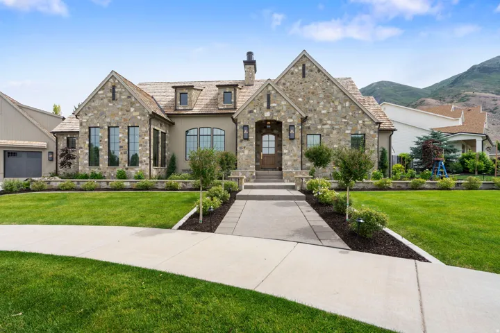 Stone and stucco exterior featuring a prominent gabled roofline and multiple dormer windows