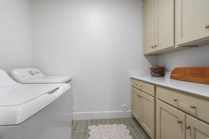 Laundry area featuring light-toned cabinetry, a white countertop, and tiled flooring