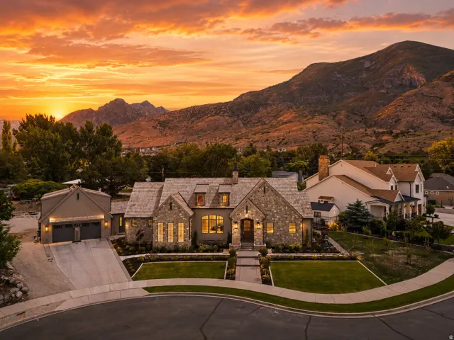 Stone and stucco exterior residence featuring a multi-gabled roofline and prominent chimney
