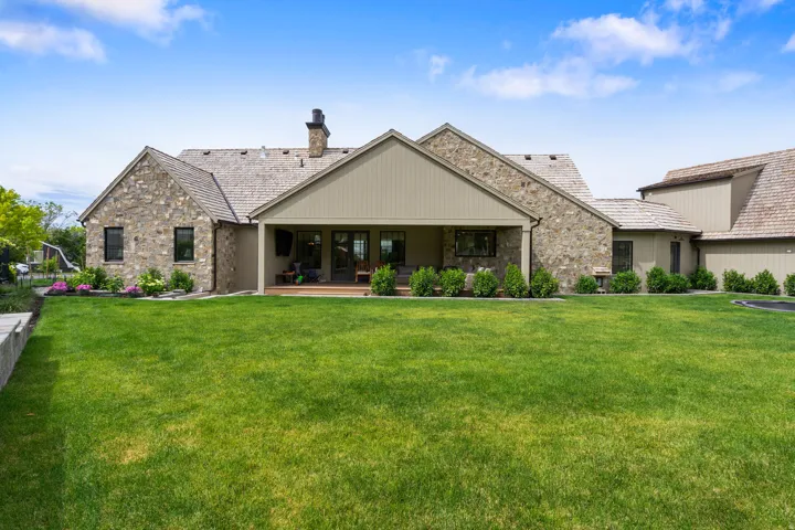 Expansive green lawn with a covered patio featuring a wood-finish floor and recessed lighting