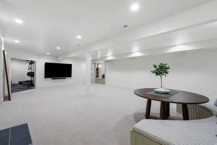 Spacious lower level featuring plush carpeting, recessed lighting, and a wall-mounted media area