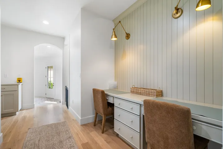 Built-in desk area featuring beadboard wall paneling, two sets of drawers, and brass wall sconces