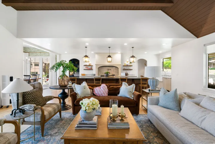 Spacious living area featuring wood-finish flooring, vaulted ceilings with exposed wood beams, and recessed lighting