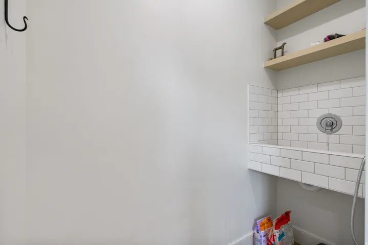 Built-in wash station featuring white subway tile, a chrome faucet, and integrated handheld sprayer