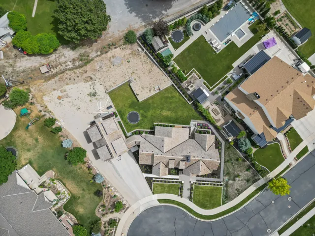 Aerial view showcasing a property with a multi-gabled roofline and an expansive paved driveway