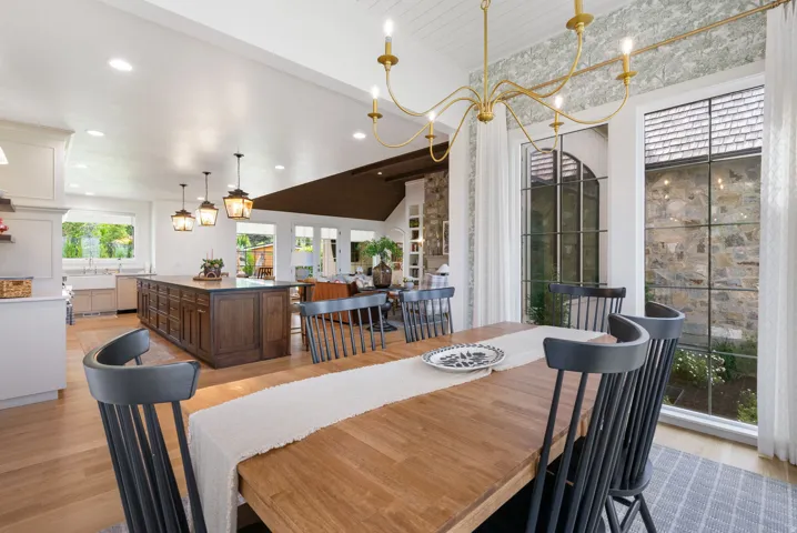 Dining area featuring a gold-finish chandelier, a large window with a stone exterior visible, and wood-finish flooring