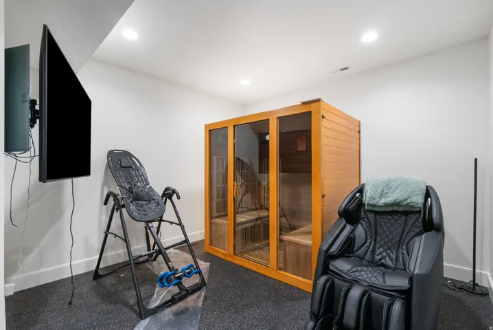 Dedicated fitness space featuring a built-in wood-paneled sauna with glass doors, recessed lighting, and dark-finish flooring