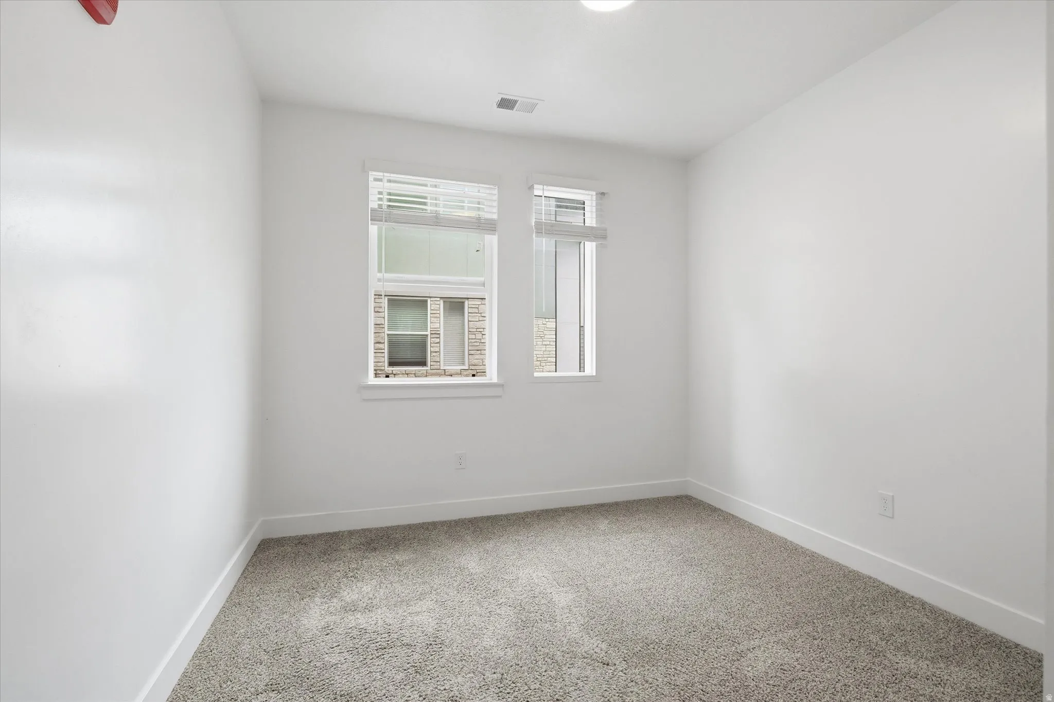 Neutral-toned carpeting extends throughout this interior space, complemented by crisp white walls and white baseboards