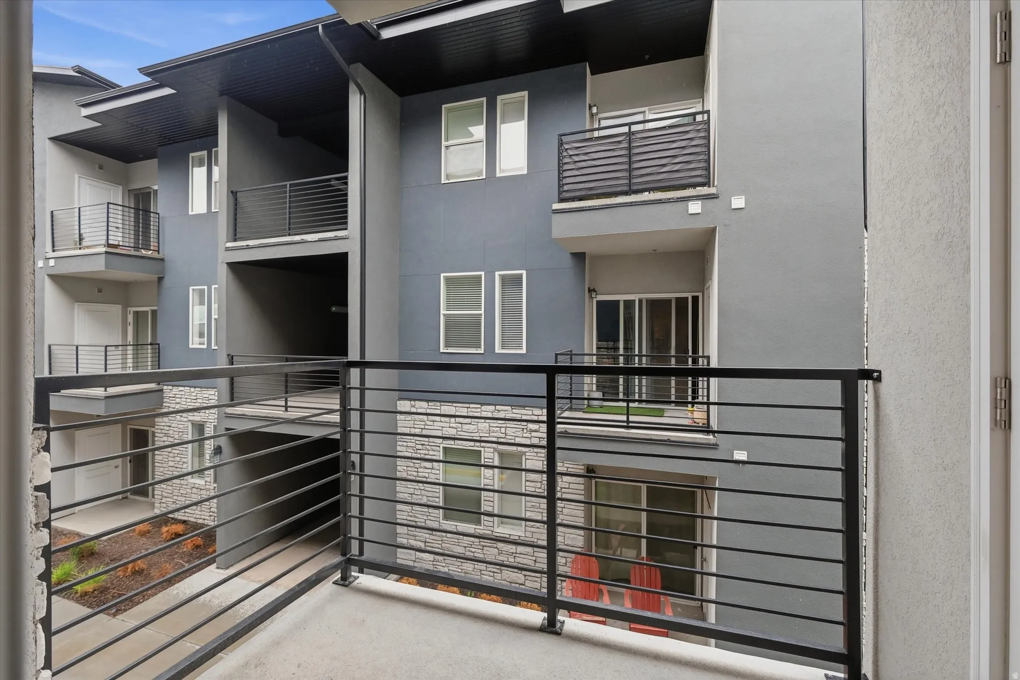 Exterior balcony featuring metal railings and a textured concrete surface
