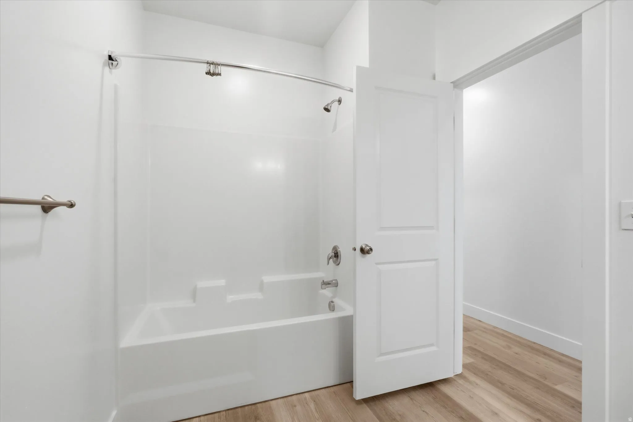 Bright bathroom featuring a white tub and shower combination with a curved shower rod