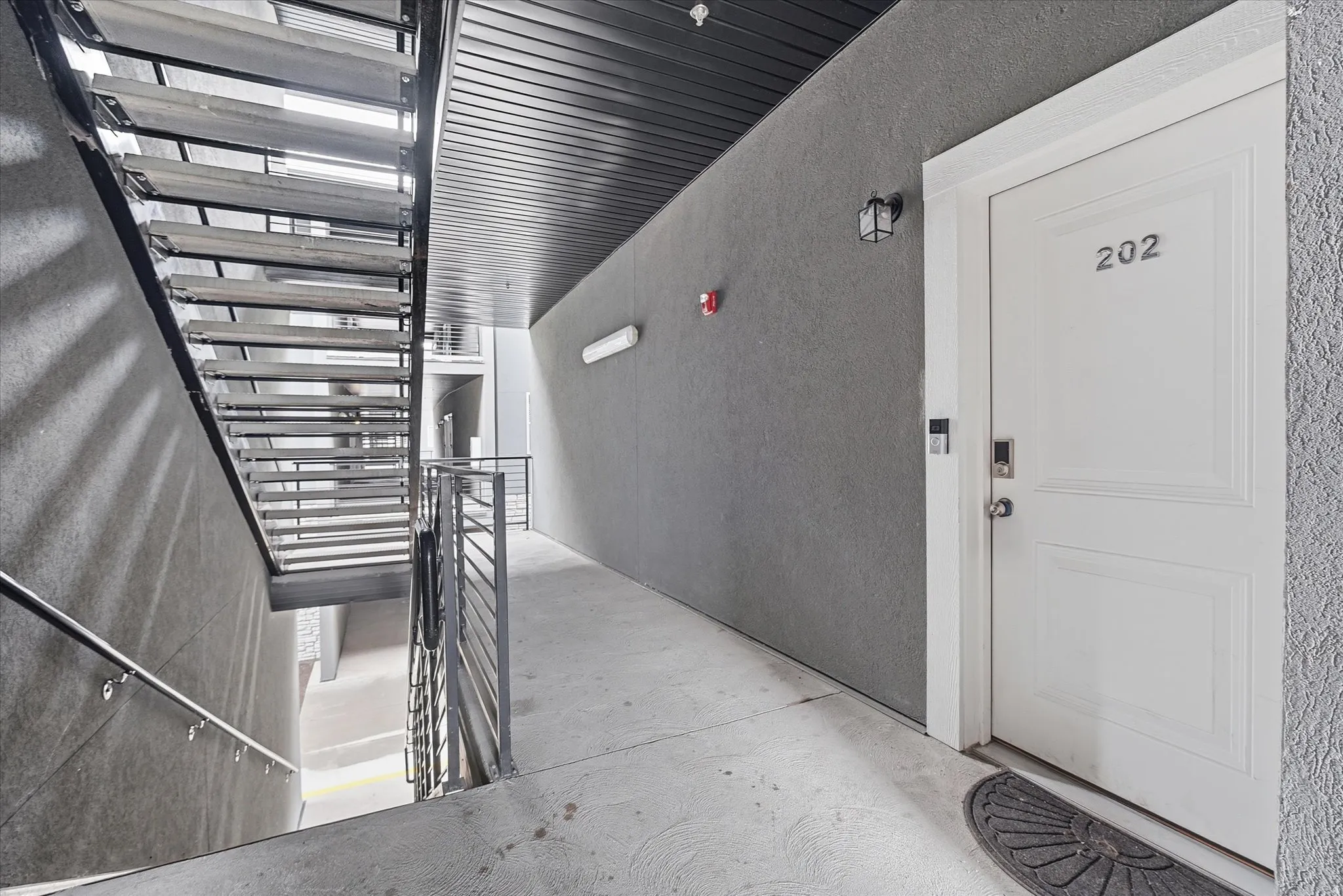 Entryway featuring a white paneled door with integrated keyless entry, dark gray textured wall, and concrete flooring