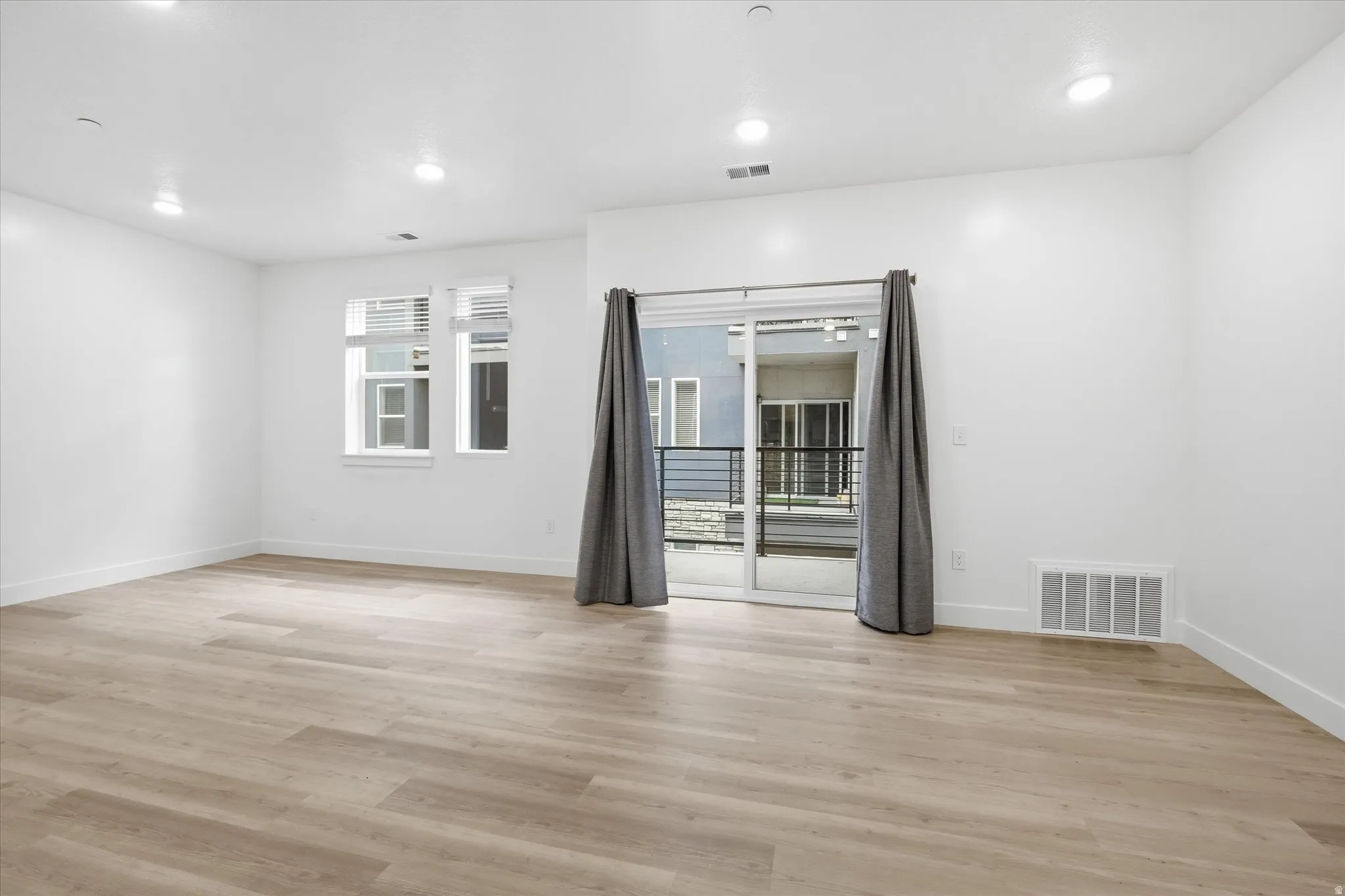 Spacious interior featuring wood-finish flooring, recessed lighting, and white baseboards