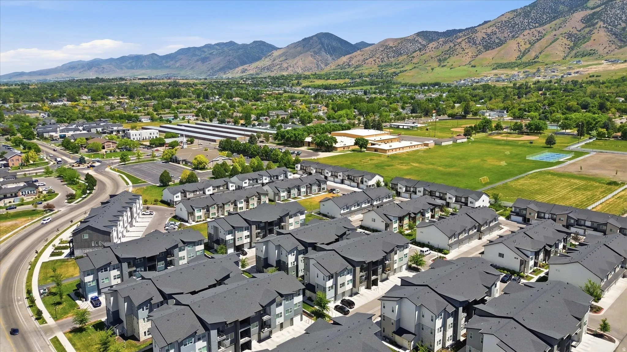 Aerial perspective of a multi-unit residential community featuring dark-toned roofs and light-colored siding