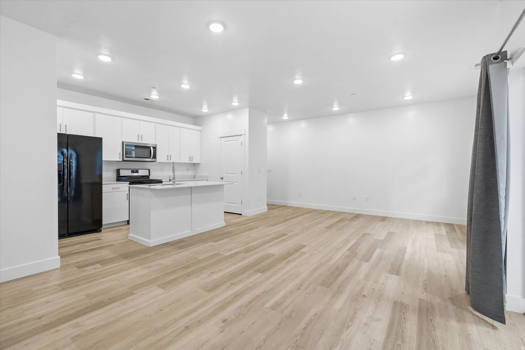 Open concept living space featuring wood-finish flooring, recessed lighting, and a modern kitchen