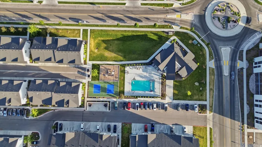Aerial view showcasing a community with townhomes, a central amenity building, and a swimming pool