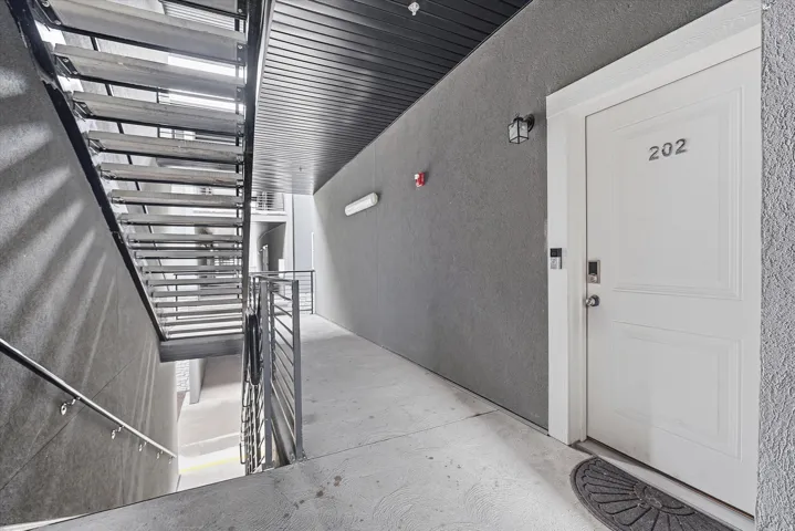 Entryway featuring a white paneled door with integrated keyless entry, dark gray textured wall, and concrete flooring