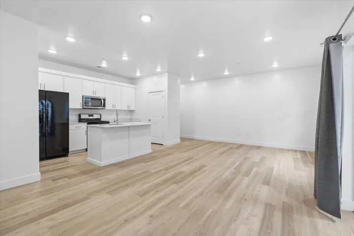 Open concept living space featuring wood-finish flooring, recessed lighting, and a modern kitchen