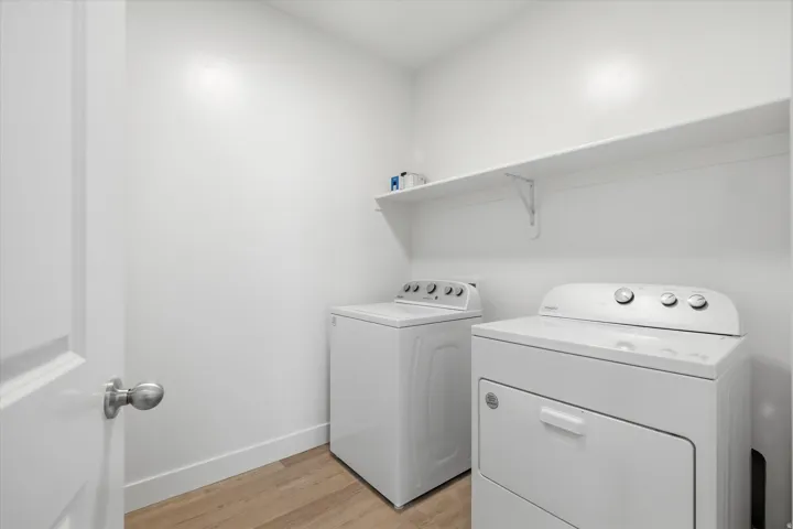 Dedicated laundry space featuring a floating shelf, light wood-finish flooring, and white baseboards