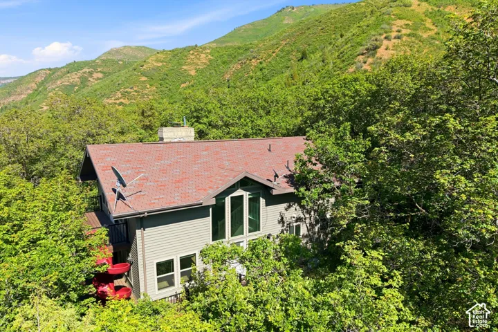 Home exterior featuring light grey siding, a red shingled roof, and a prominent chimney