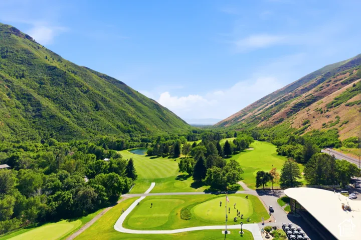 Expansive golf course setting featuring manicured greens and fairways surrounded by lush, tree-covered mountains