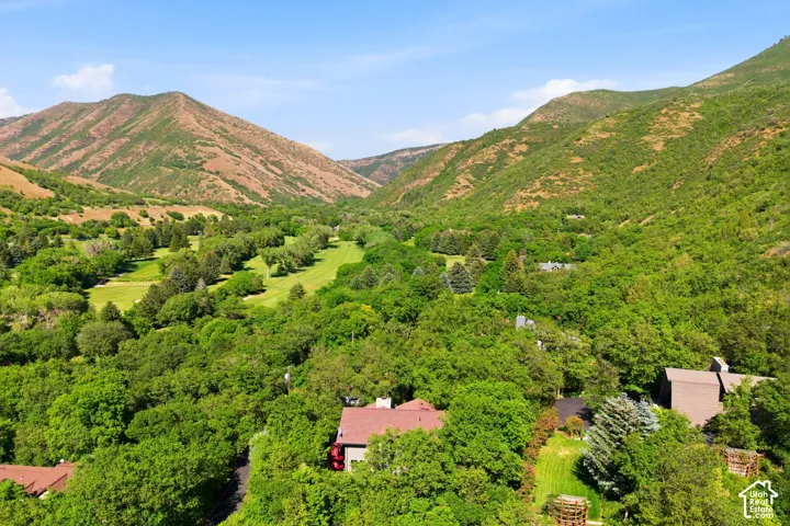 Expansive mountain landscape featuring lush green golf course fairways and dense forestation