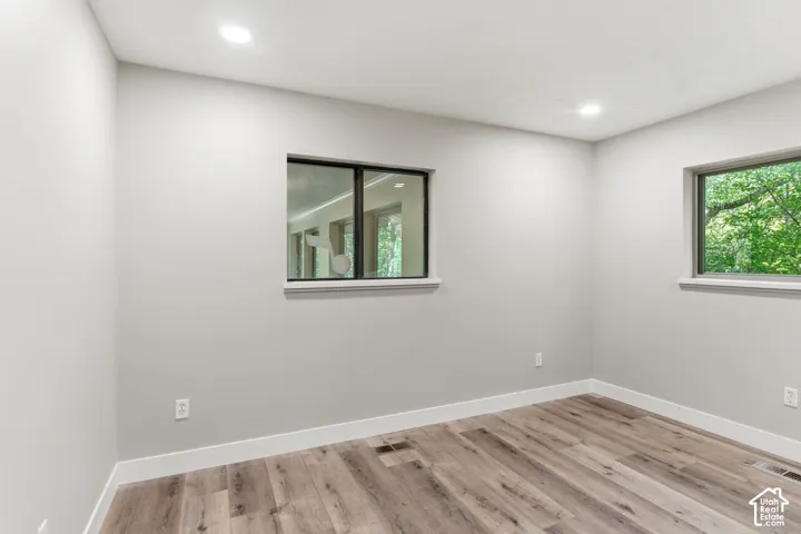 Room featuring light gray walls, wood-finish flooring, and white baseboards