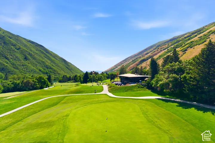 Expansive golf course featuring manicured greens and fairways framed by verdant mountains