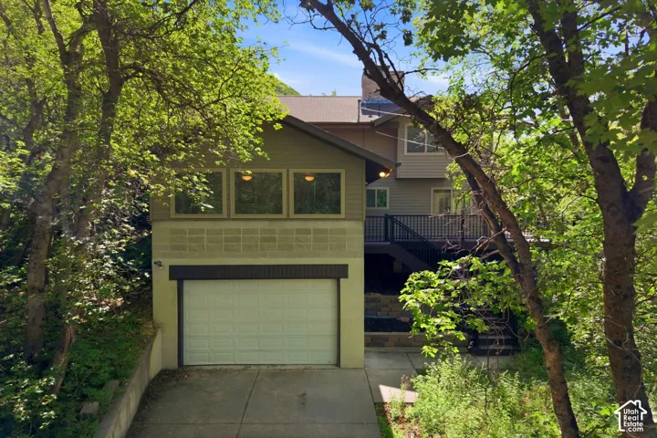 Multi-level residence featuring a two-car garage, tiered deck, and a mix of siding and block exterior finishes