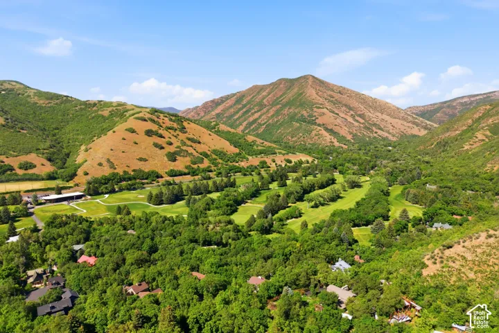 Expansive golf course property surrounded by lush green trees and natural mountain terrain