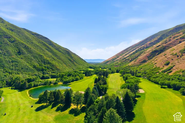 Expansive golf course setting featuring lush green fairways, mature evergreen trees, and a clear water feature