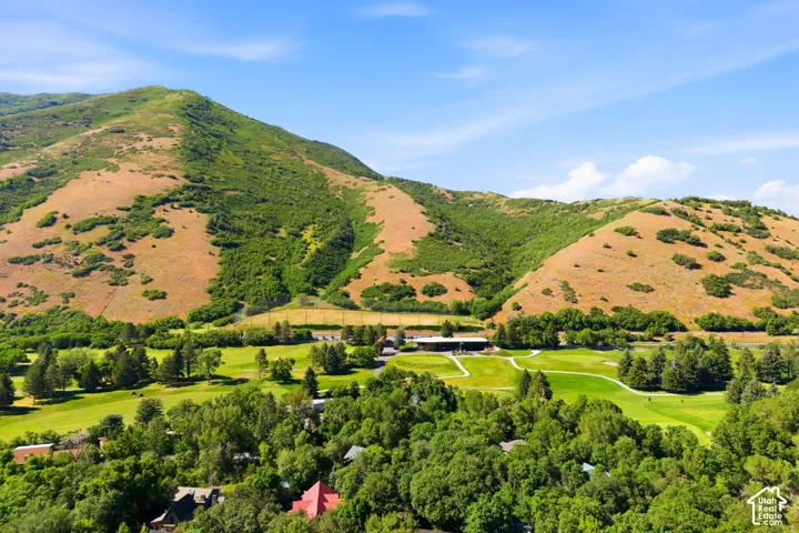 Expansive mountain landscape with a verdant golf course and surrounding mature trees
