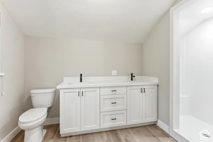 Dual sink vanity with white cabinetry, matte black fixtures, and light-toned countertops