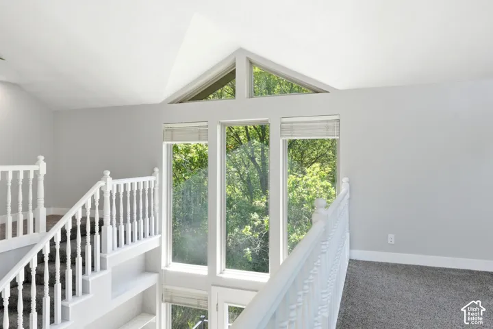 Interior space featuring tall vaulted ceilings, a prominent staircase with white balusters, and large windows with transom architectural details