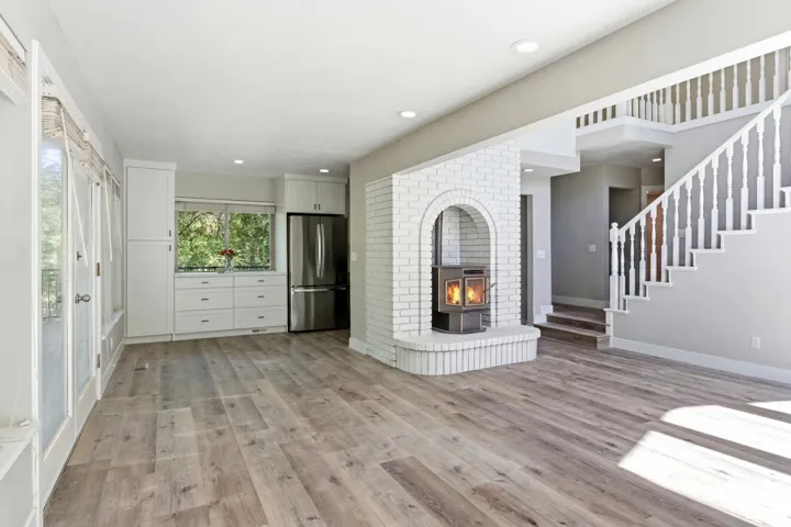 Spacious interior featuring wide-plank wood-finish flooring and a white brick fireplace with an arched opening