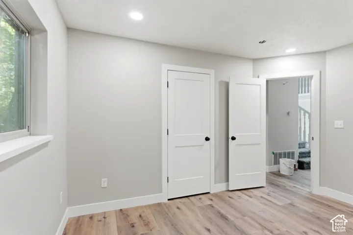 Room featuring wood-finish flooring, recessed lighting, and a white window trim
