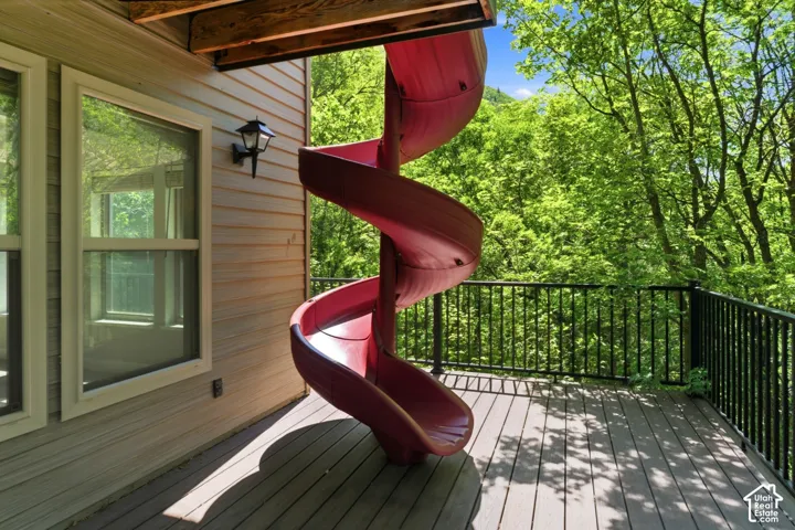 Spacious outdoor deck featuring a red spiral slide, durable composite decking, and black metal railings, surrounded by mature trees