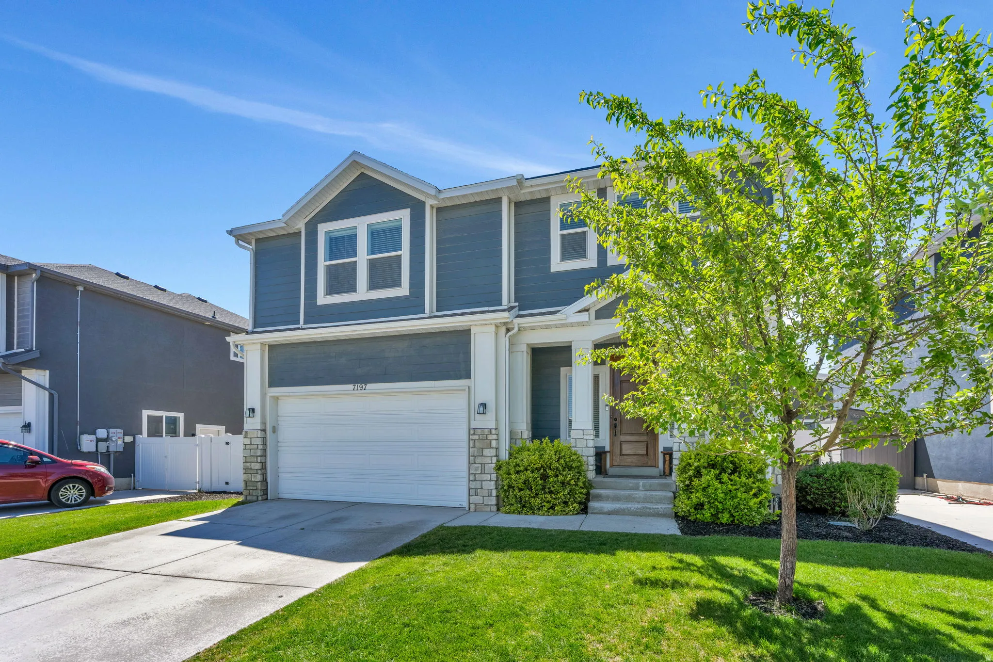 Two-story residence featuring blue siding with white trim, a stone façade accent, and a front-facing garage