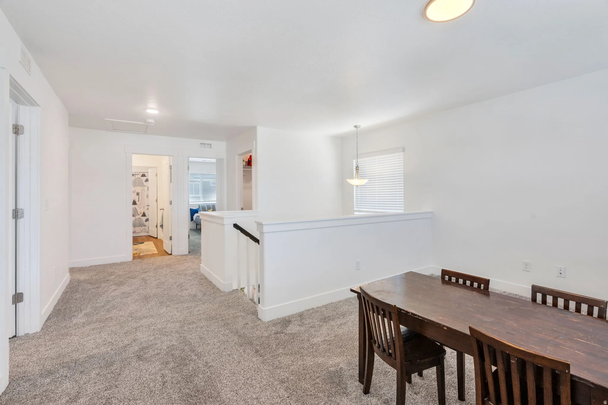 Upper-level landing featuring textured gray carpeting, white painted walls, white baseboards, and overhead recessed lighting