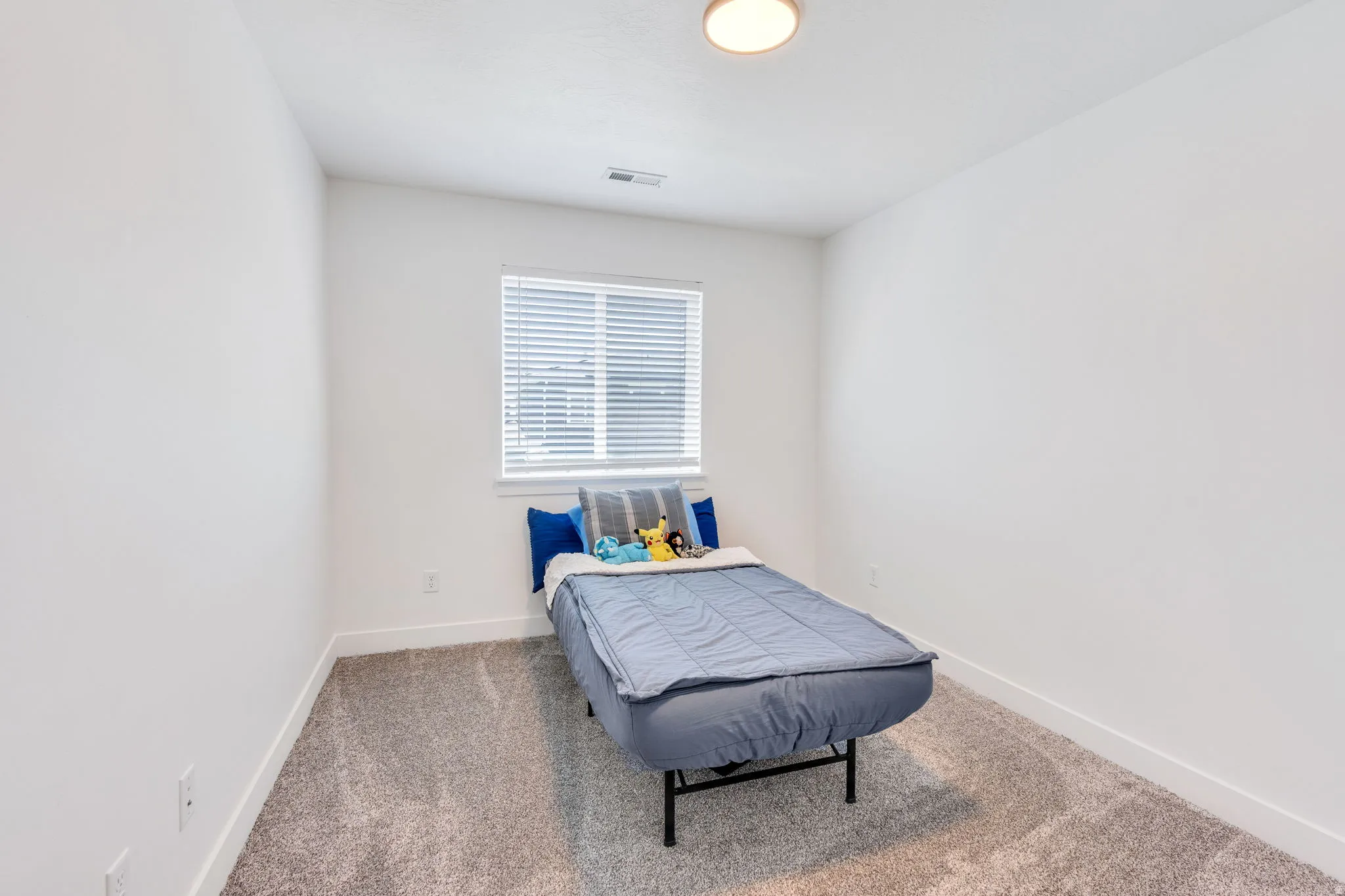 Carpeted room featuring a single window with blinds, white walls, and white baseboards