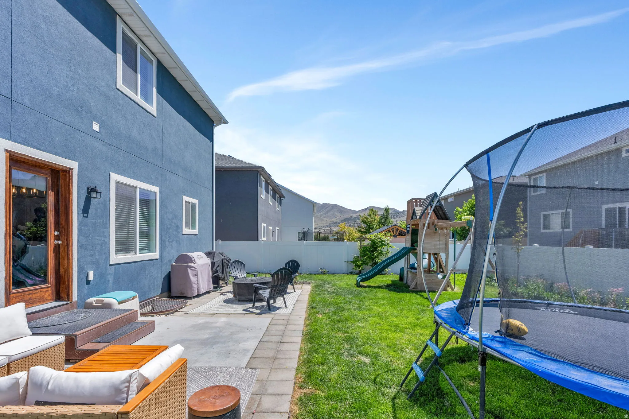 Expansive backyard featuring a stone patio, manicured lawn, and a privacy fence