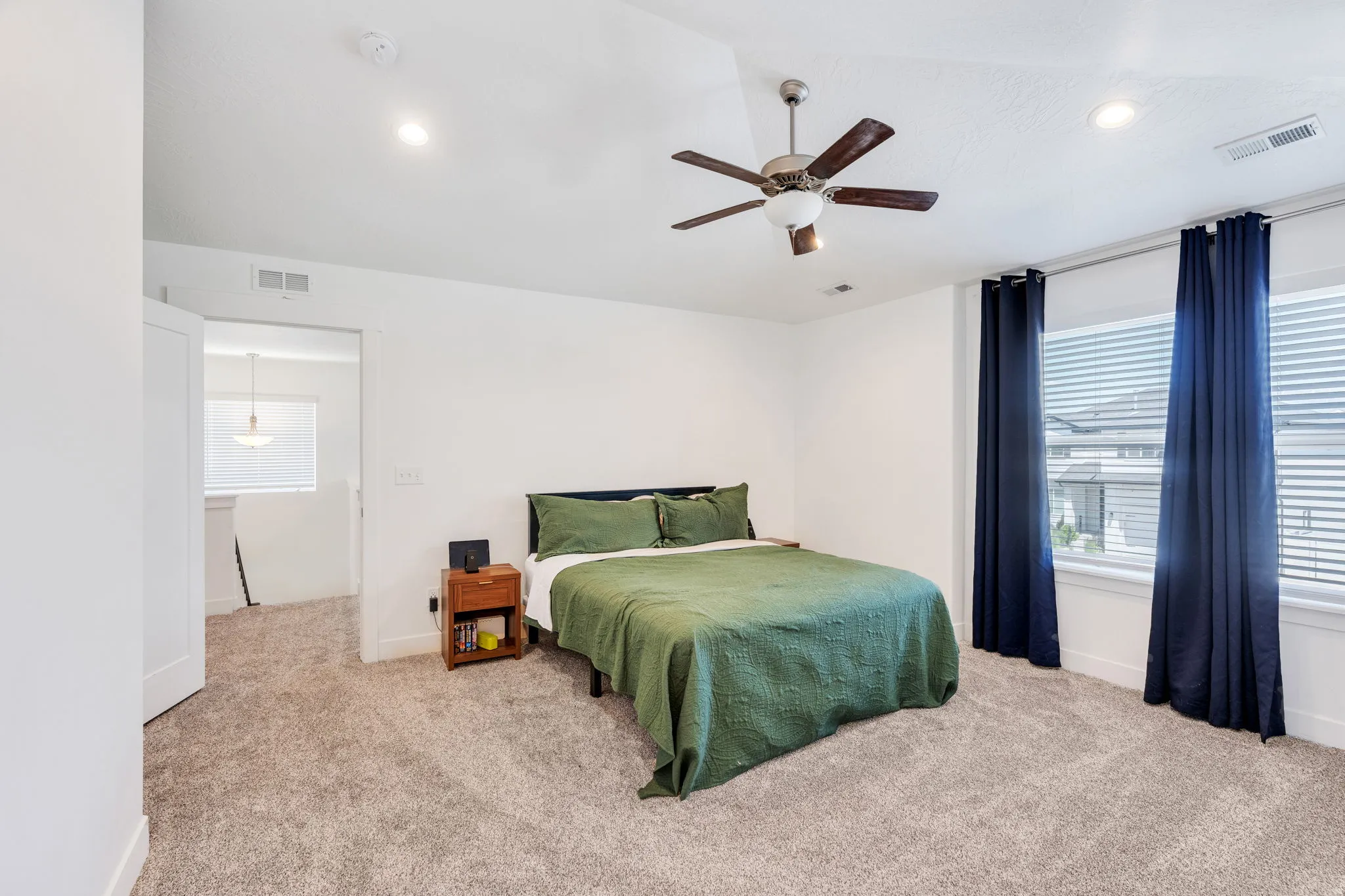 Neutral-toned carpeting throughout this room, featuring recessed lighting and a ceiling fan