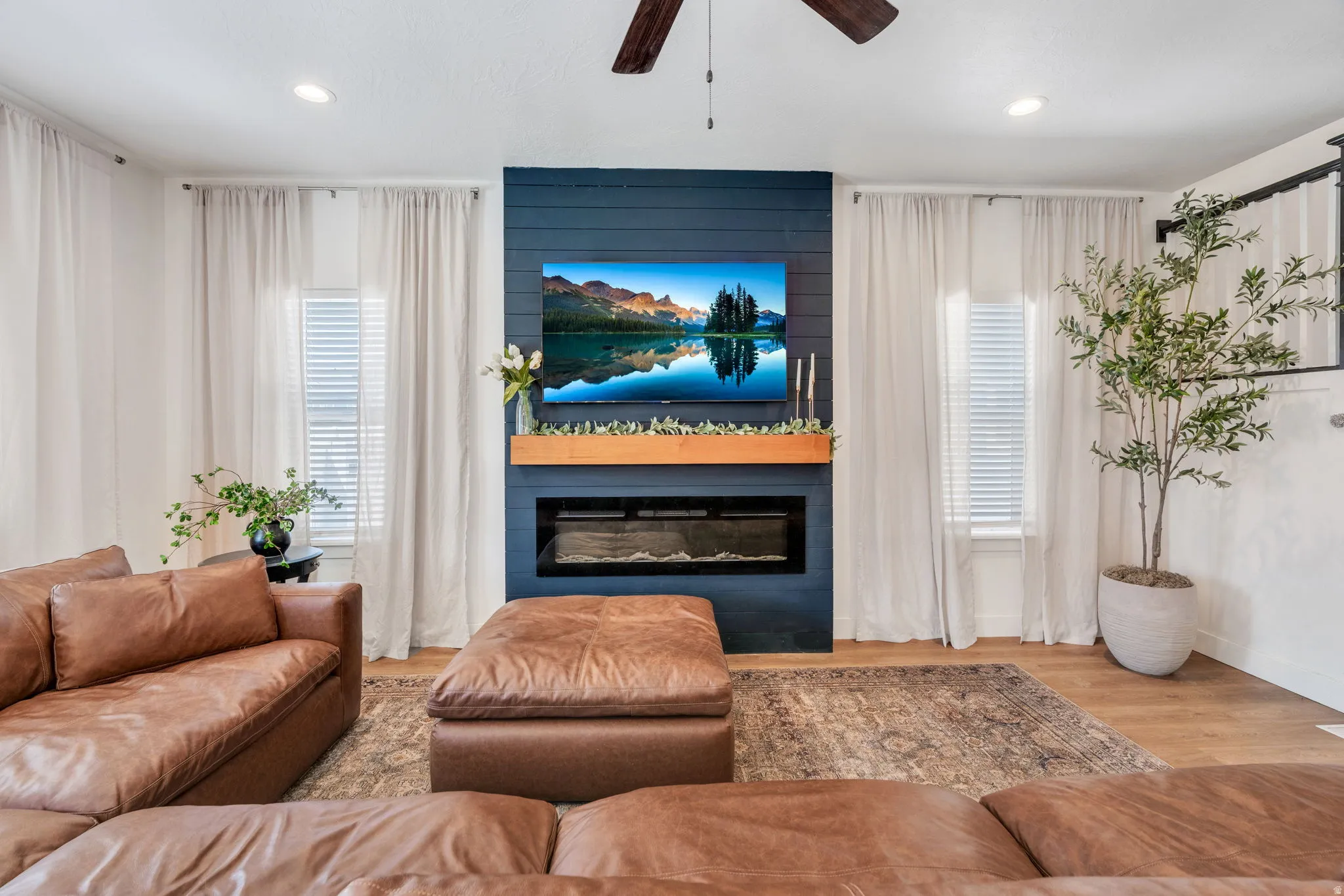 Living area featuring a shiplap accent wall with an integrated electric fireplace, a natural wood mantel, and wood-finish flooring